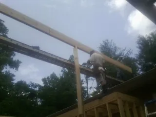 Carpenter setting a ridge beam over a new addition frame — Ice Dam Removal by Roofing Brothers in Dows