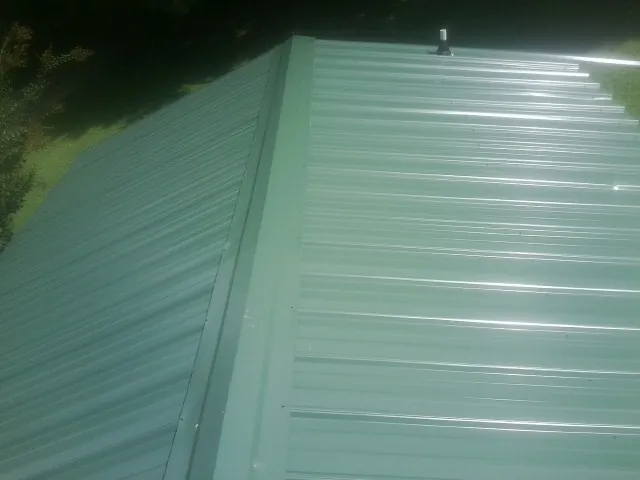 New green metal panels meeting at the ridge of a roof — Flat Roof Repair work by our crew in Dows