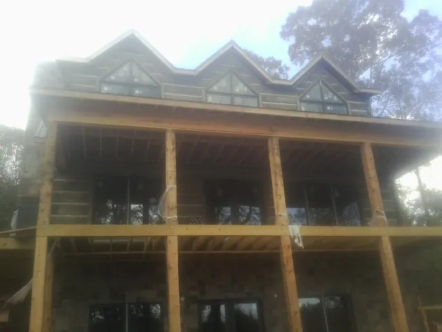 Dormers and porch framing on a large log home under construction — Roof Coating work by our crew in Dows