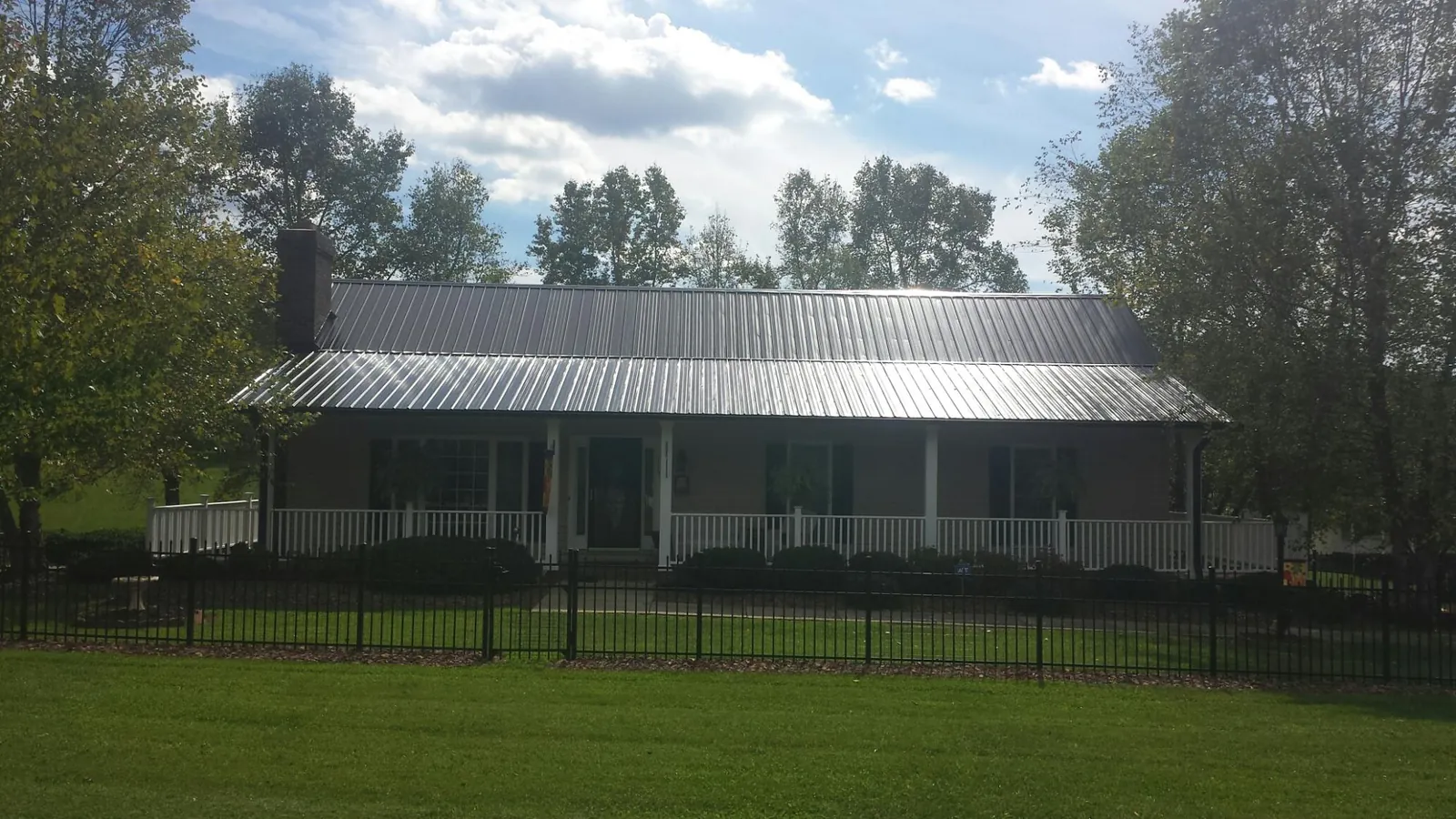 Gray metal roof on a brick ranch with a full width front porch — Gutter Guard Installation work by our crew in Dows