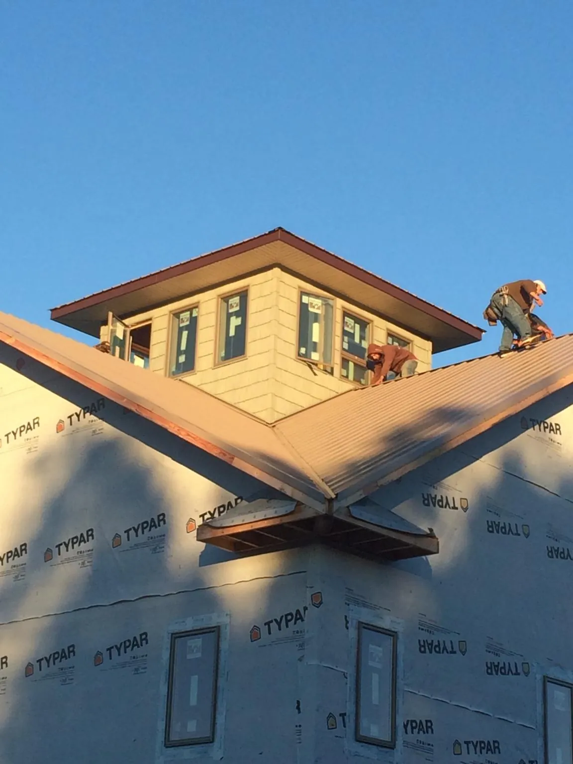 Roofers working around a rooftop cupola on a new metal roof at sunset — Roof Waterproofing in Dows by Roofing Brothers